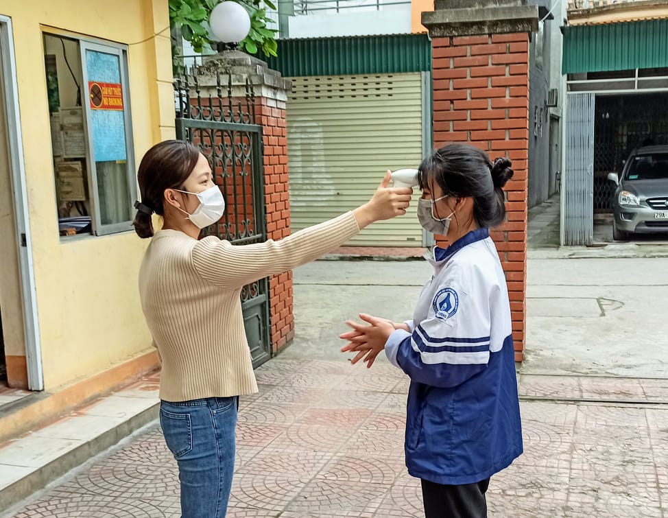 Cán bộ phòng công tác HSSV đo thân nhiệt cho học sinh trước khi vào trường